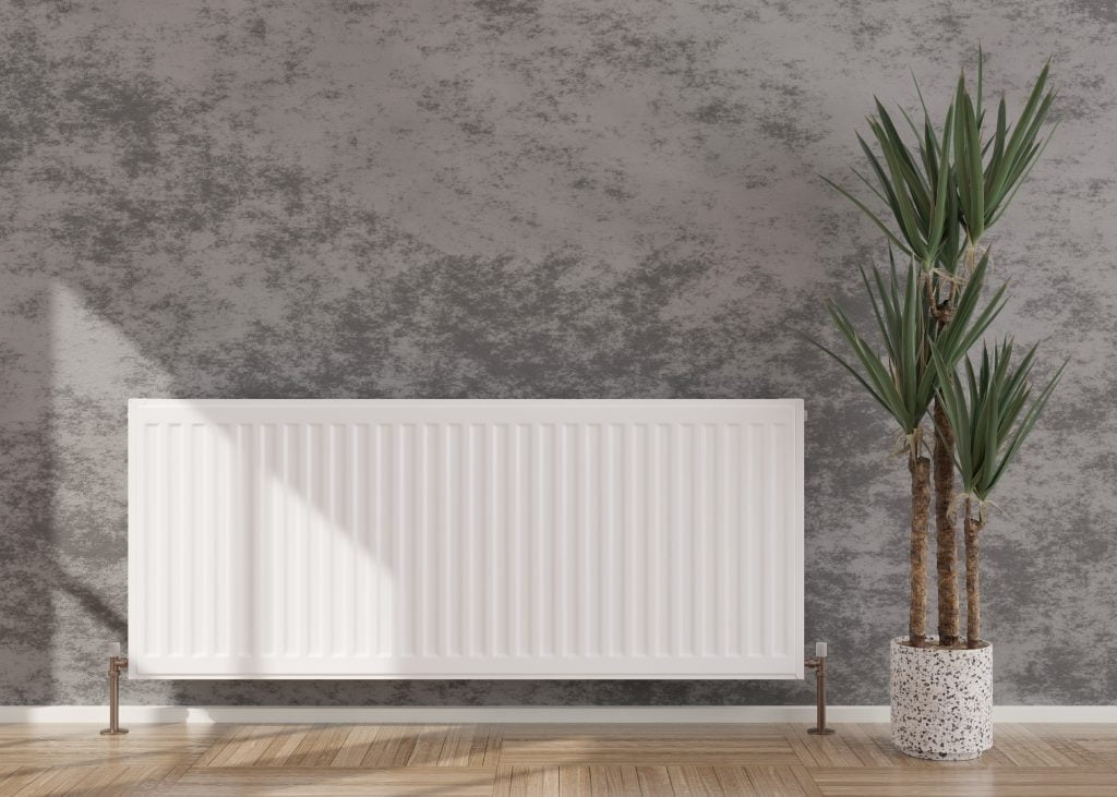 Witte radiator tegen een grijze betonlook muur