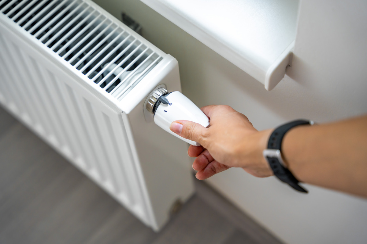 Hand die de thermostaatknop verdraait
